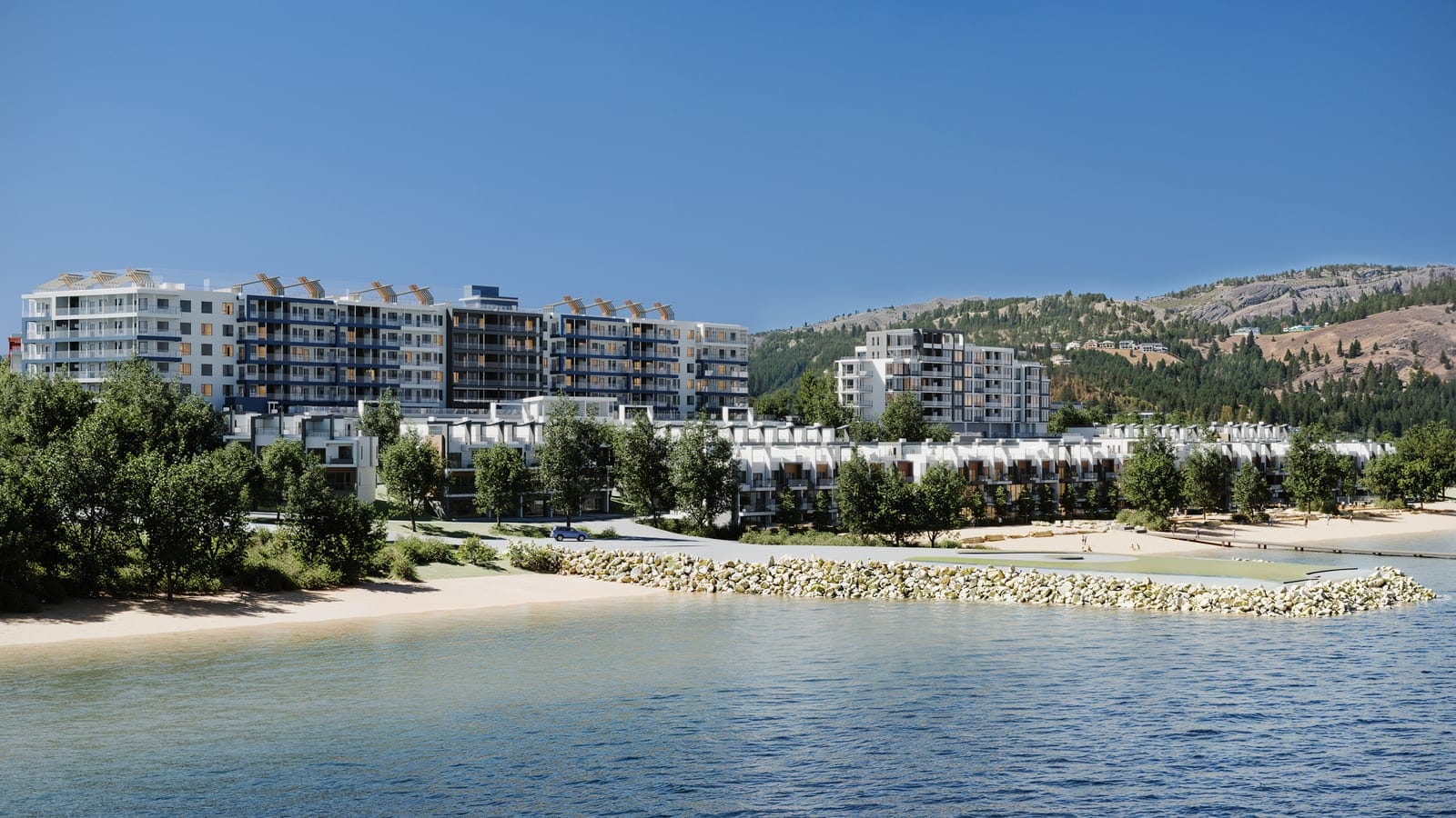 Westrich Bay from Okanagan Lake on a summer day: the beach and rock breakwater, the villas, the Waterfront Tower and the rental buildings below the West Kelowna hills