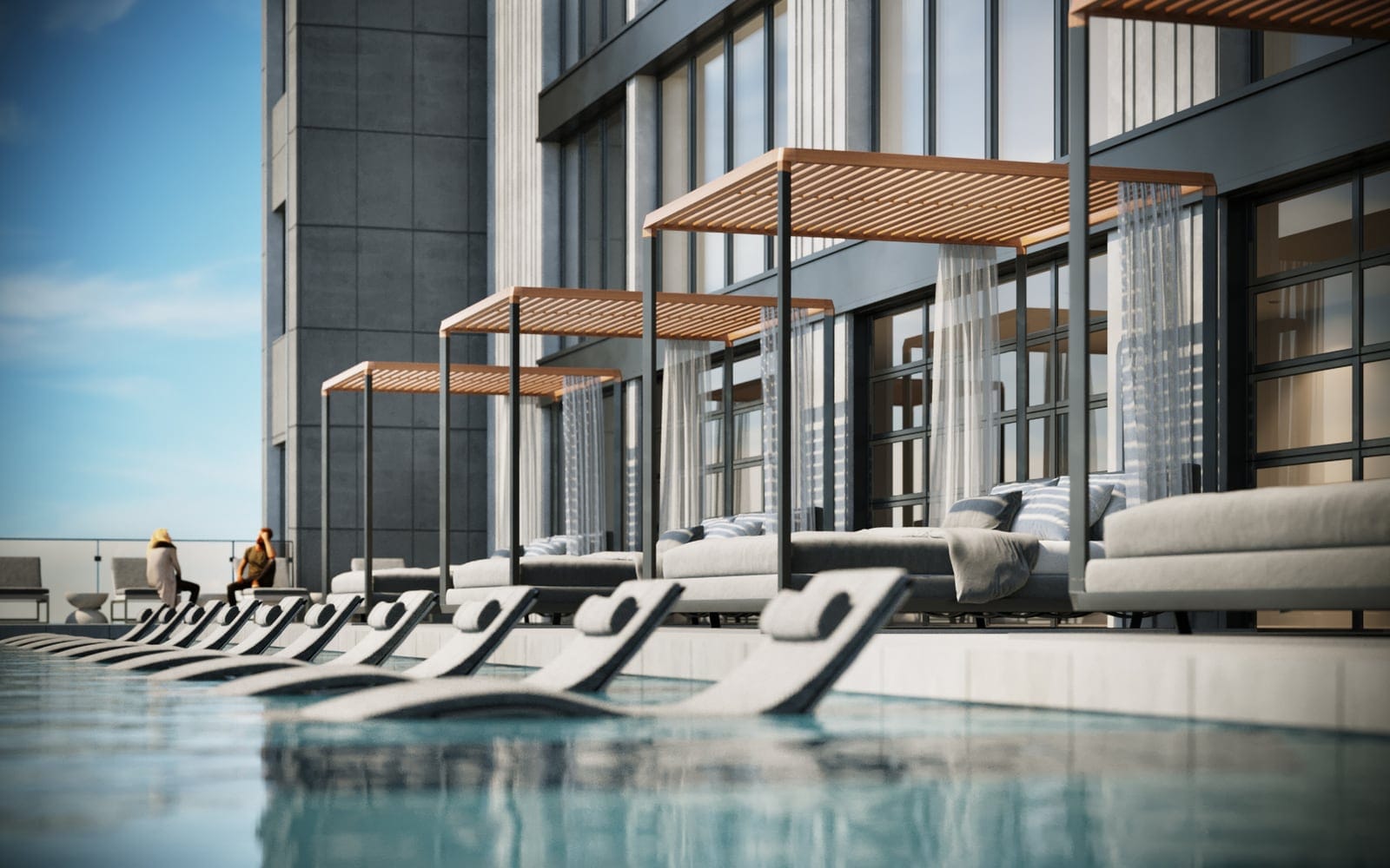 Poolside cabanas with slatted timber roofs and sheer curtains on the Waterfront Tower’s pool deck, in-water loungers in the infinity pool