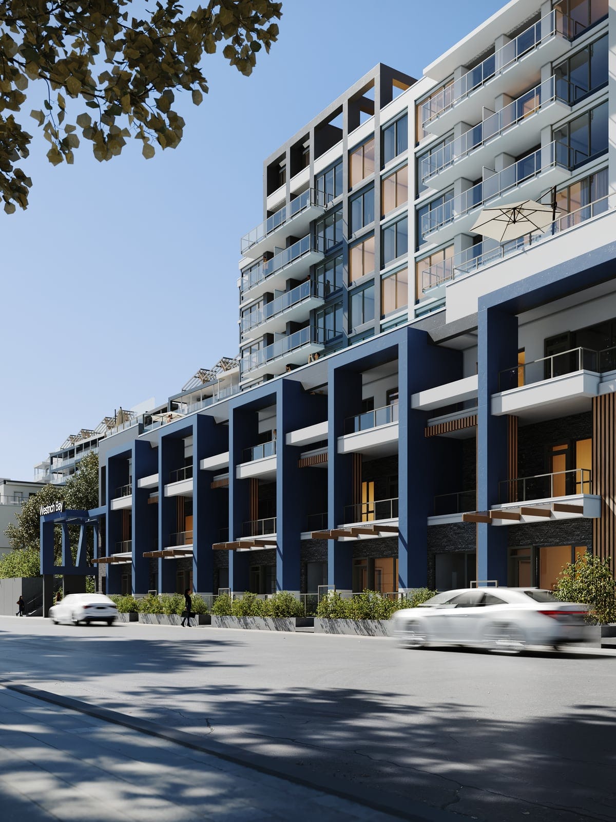 The Waterfront Tower rising above its navy-framed street-front homes, seen from the street corner on a sunny day