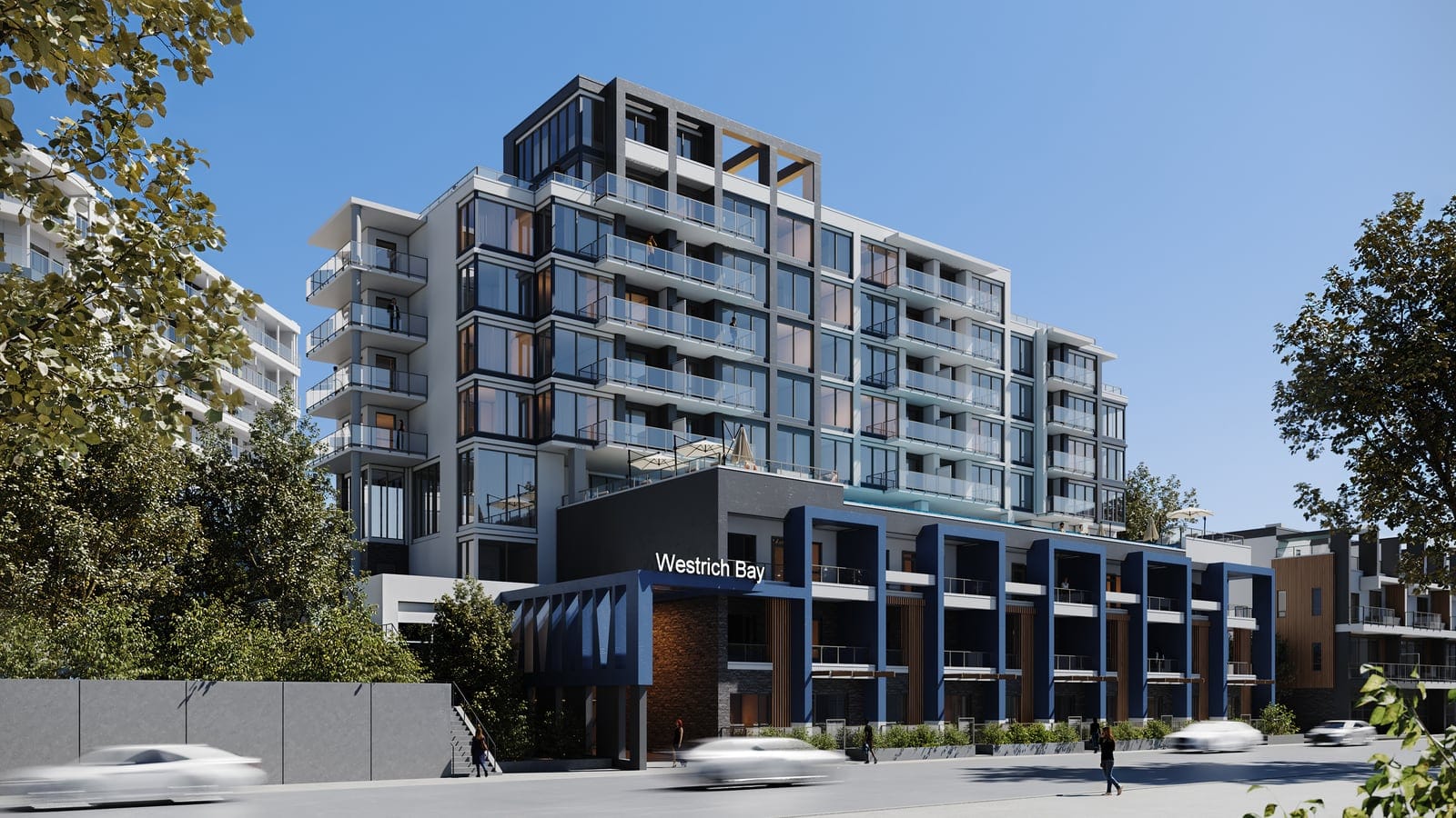 The Waterfront Tower from the street on a sunny day, the Westrich Bay sign over its entrance and navy-framed street-front homes along the sidewalk